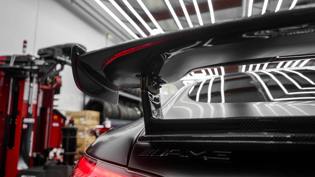 why-choose-us Detailed view of a sportscar spoiler in a professional garage setting. Perfect for automotive themes.