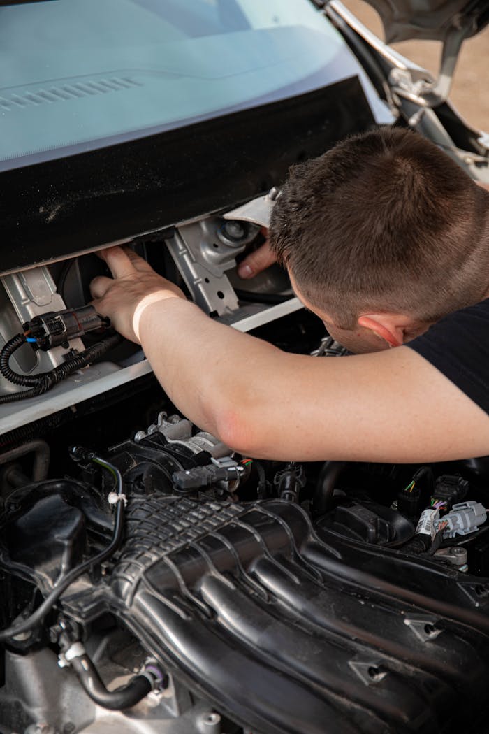 A mechanic examining a car engine with focus on details during maintenance.